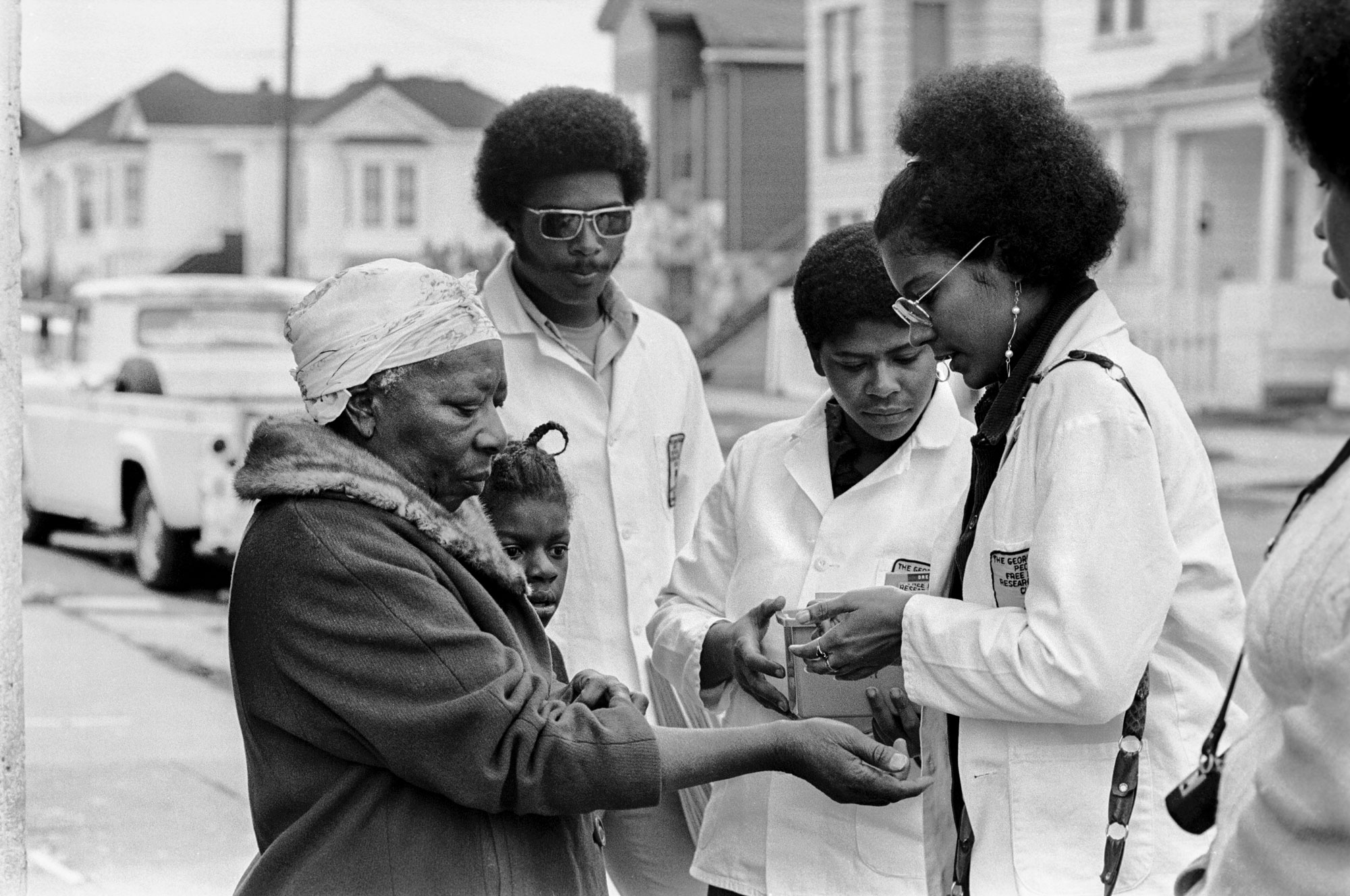 Adrienne Humphrey tests a woman for sickle cell anemia testing during Bobby Seale’s campaign for Mayor of Oakland, California, 1973. © Stephen Shames